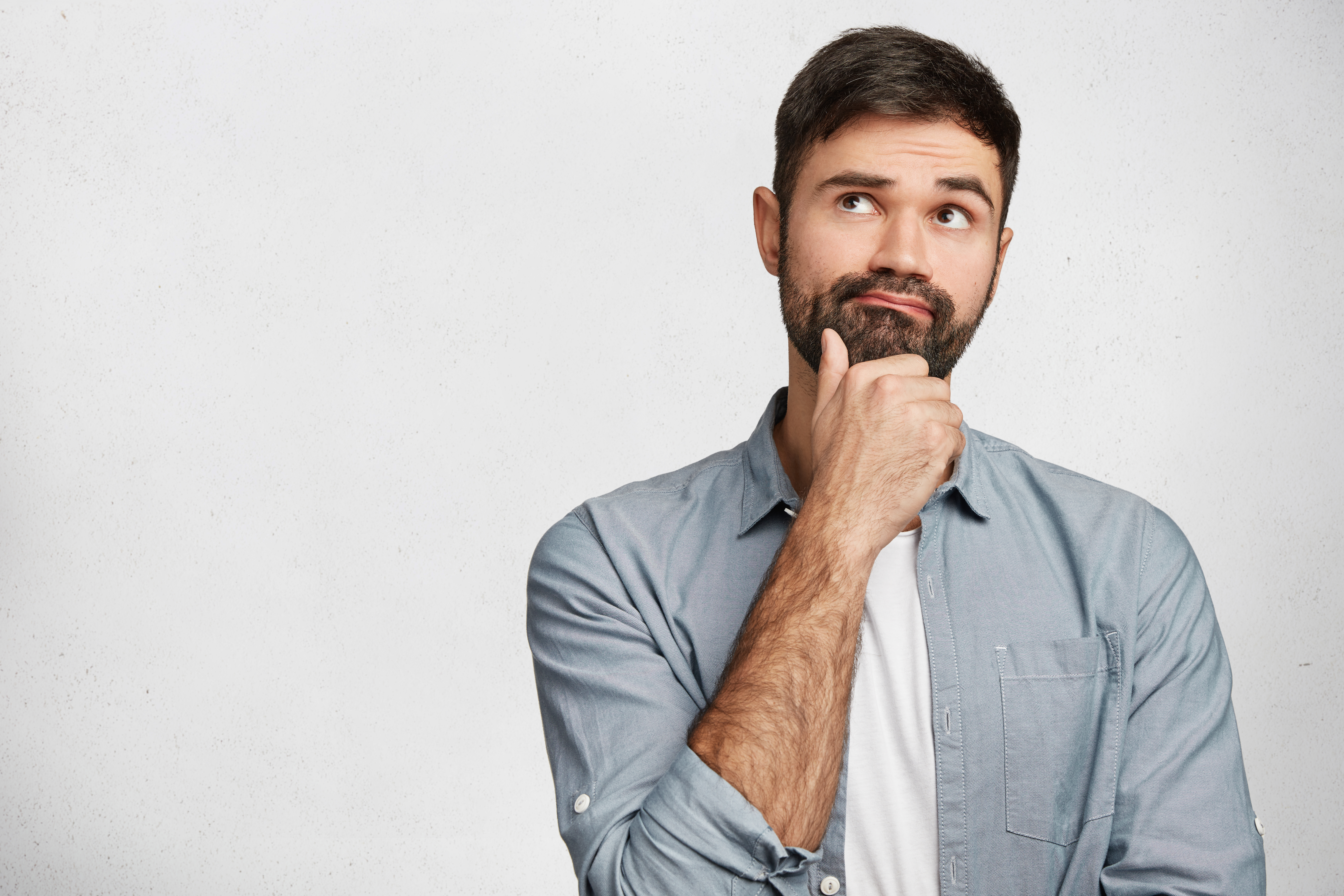 Thoughtful Man With Stubble Looks Pensively Upwards, Has Pleasant Dreams As Plans His Coming Holidays, Generates New Ideas, Isolated Over White Background With Copy Space For Your Advertising Content - PV Assessoria Contábil | Contabilidade no Rio de Janeiro